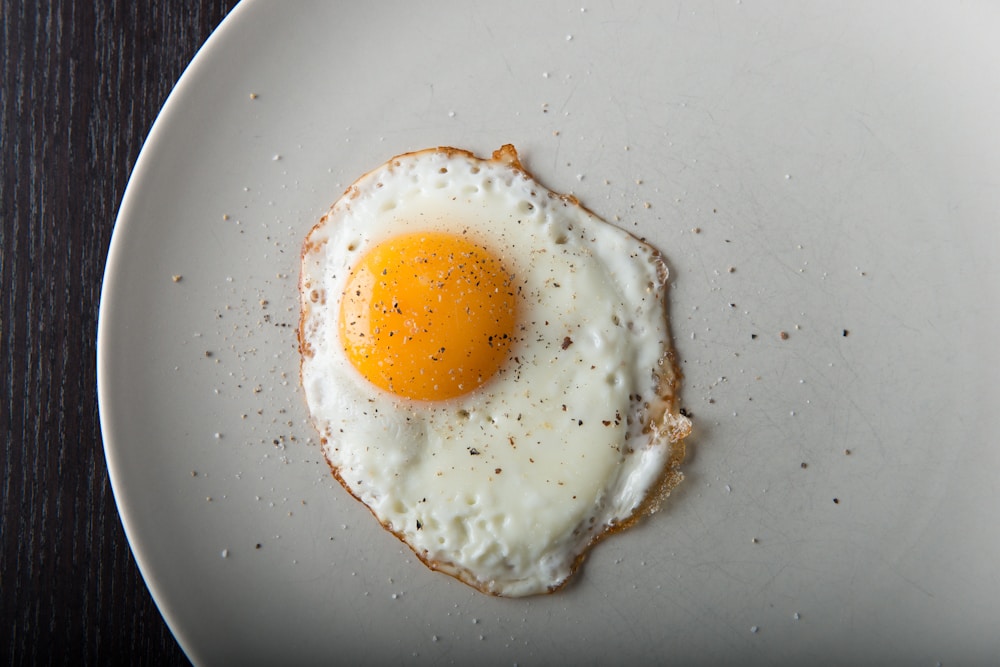 Fried egg on a plate, higher in calories than a boiled egg