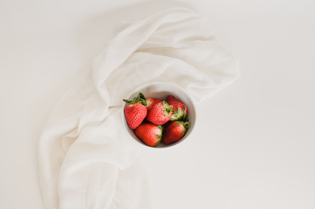 Bowl of fresh strawberries on a white cloth, an example of a whole food tracked through a database rather than a label