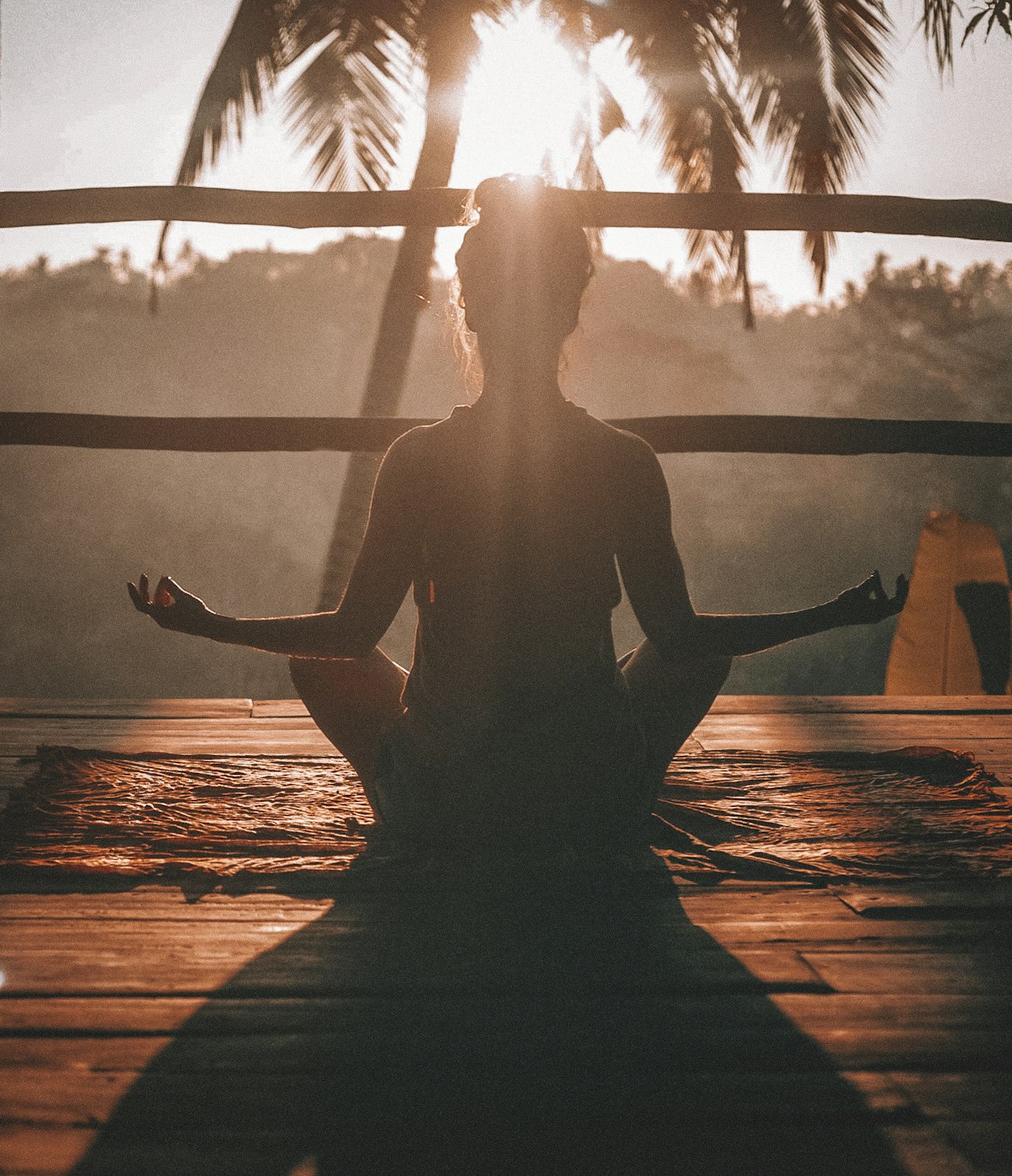 Person meditating at sunrise, a picture of the physical and mental balance behind the wellbeing meaning