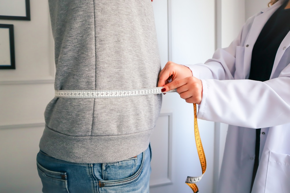 Mujer midiendo su cintura con cinta métrica, lo que la calculadora de peso ideal no ve