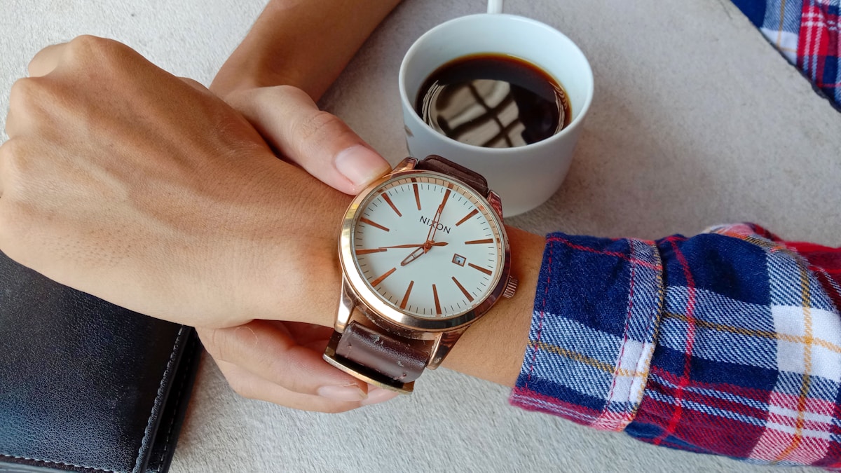 Person checking the time with black coffee, an intermittent fasting calculator routine